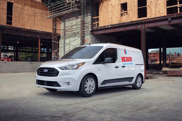 Una Ford Transit Connect Cargo Van 2023 en Frozen White con gráficos comerciales no originales estacionada en un sitio de construcción