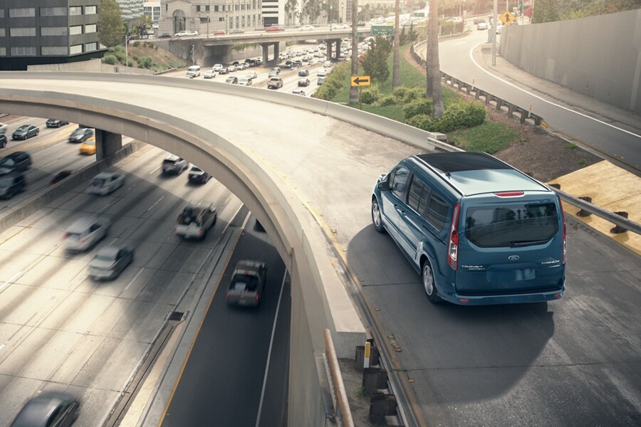 Blue Metallic 2023 Ford Transit Connect Passenger Wagon being driven over an expressway on a sunny day