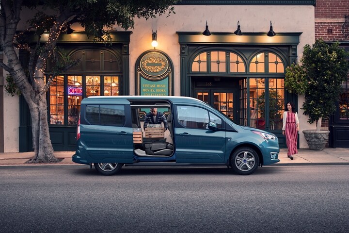 Se muestra un Wagon para Pasajeros Ford Transit Connect Titanium 2023 en Blue estacionado en una calle de ciudad