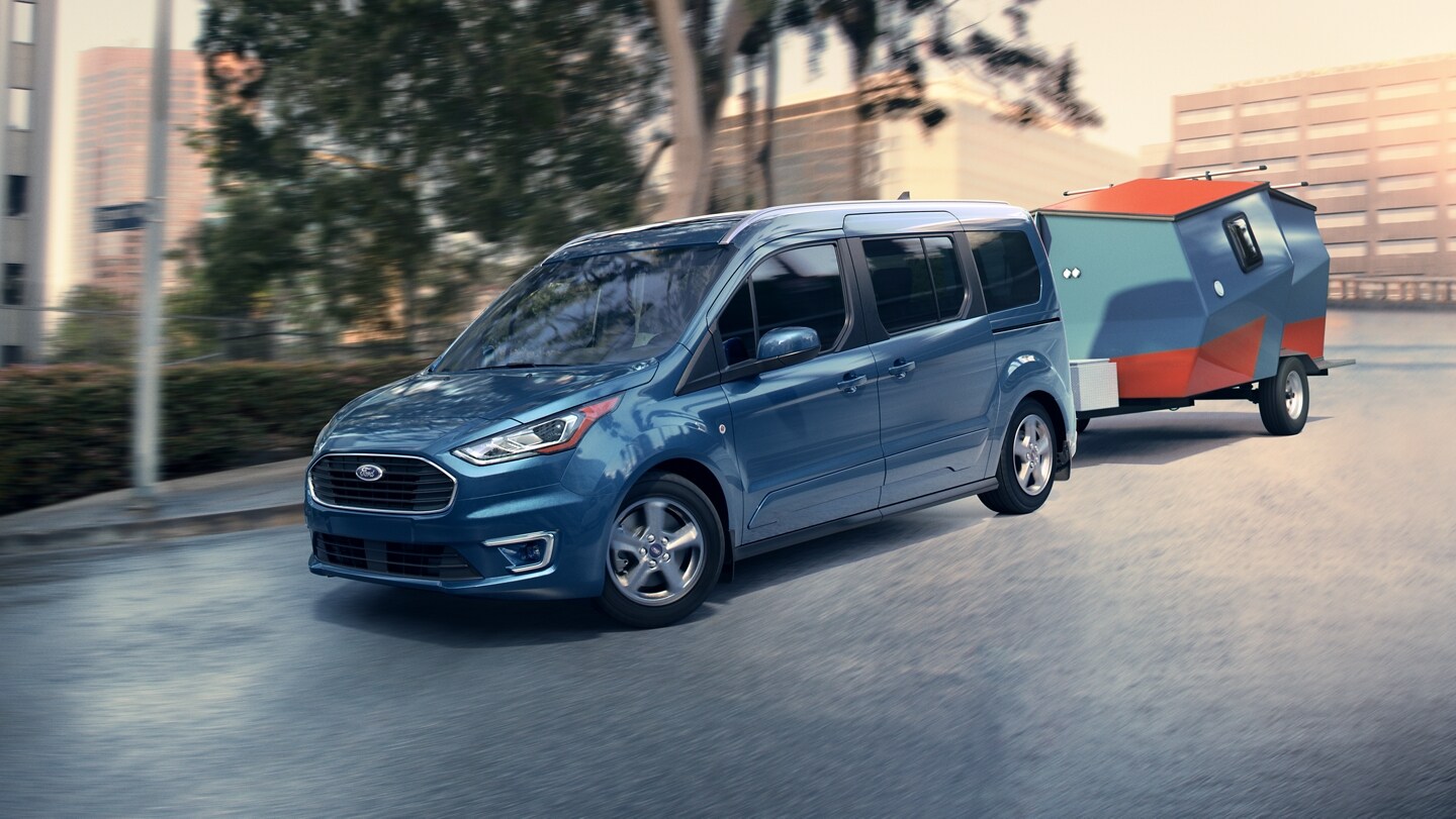 2023 Ford Transit Connect Passenger Wagon in Blue Metallic towing a trailer on a city street