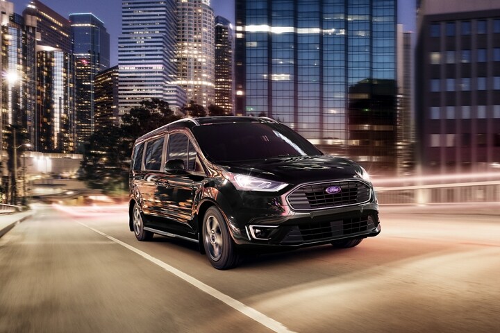Standard 5 bar grille shown here on 2023 Ford Transit Connect Titanium Passenger Wagon model being driven in city at night