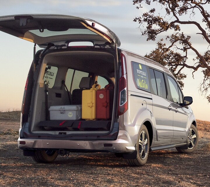 Married couple taking pictures beside a 2023 Ford Transit Connect Titanium Passenger Wagon with available rear liftgate
