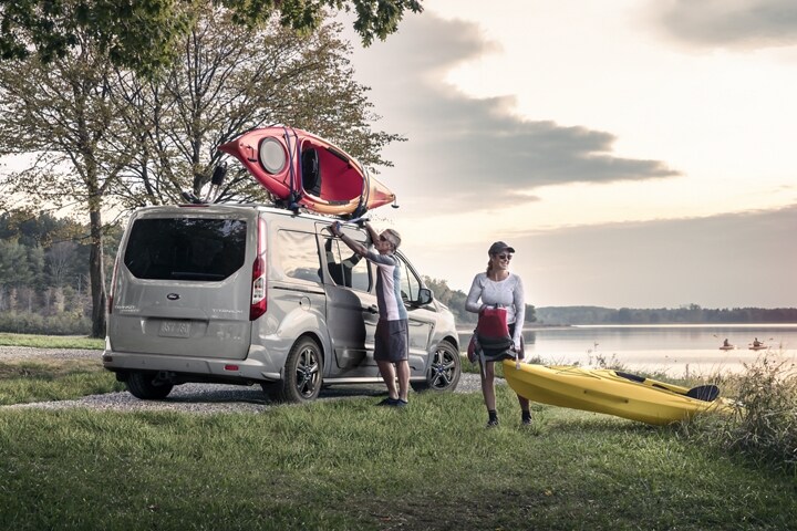 Una pareja de personas que practica kayak en un lago con un Wagon para Pasajeros Ford Transit Connect 2023 en Solar Silver