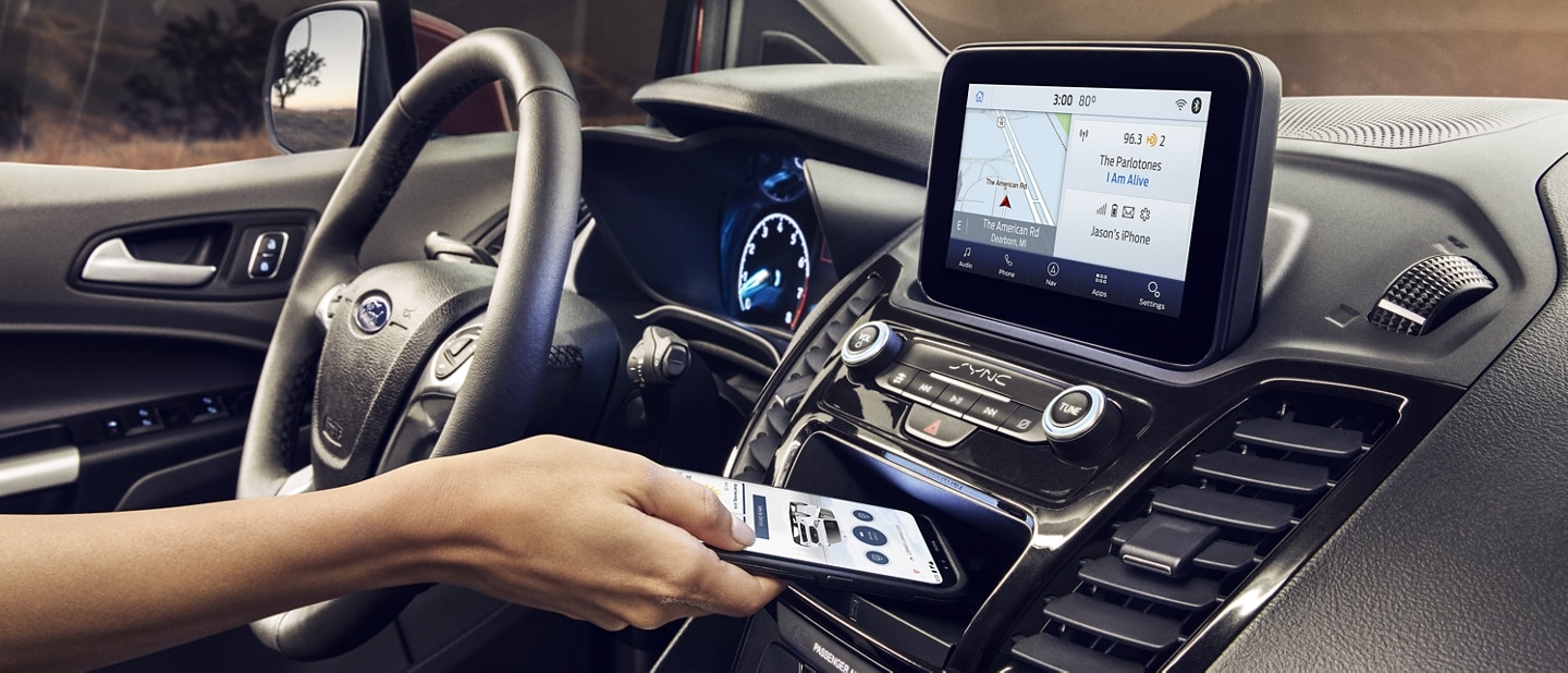 A hand holds a smartphone displaying the FordPass™ App