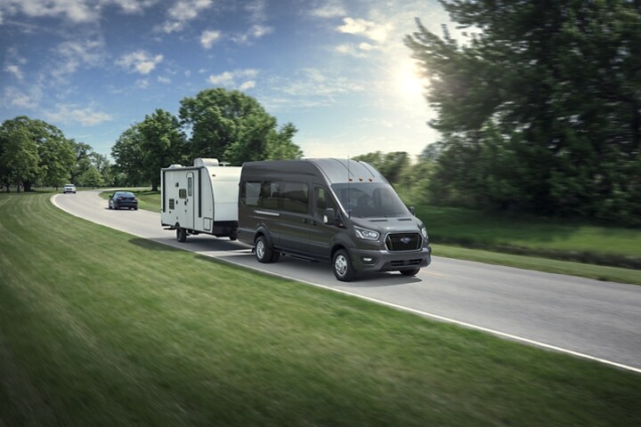 A 2023 Ford Transit® van towing a medium-sized camper