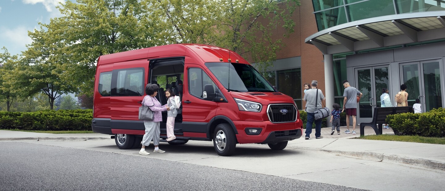 Una mujer ayudando a un niño afuera de una van Ford Transit® 2023
