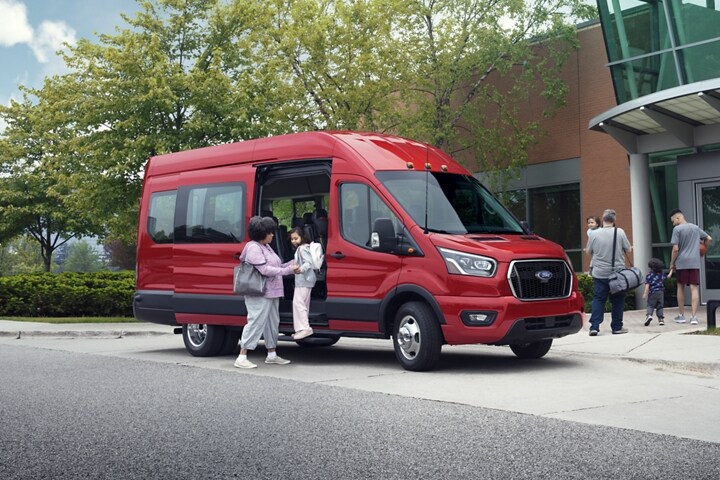 Dos personas bajando de una van Ford Transit® 2023 cerca de un centro comunitario