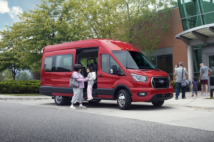 Two people getting out of a 2023 Ford Transit® van near a community center