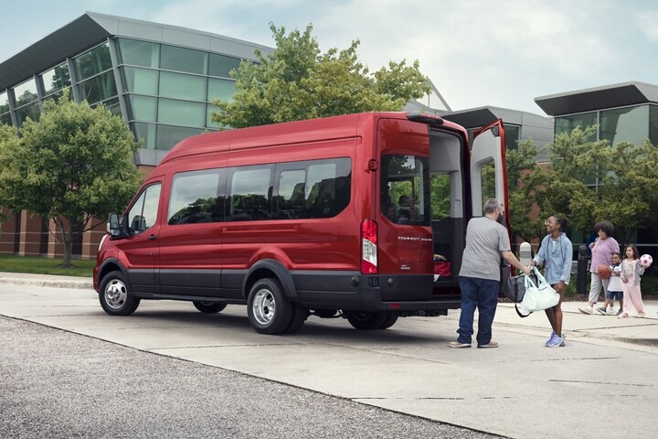 Una familia grande caminando hacia una van Ford Transit® 2023 con las puertas de carga abiertas