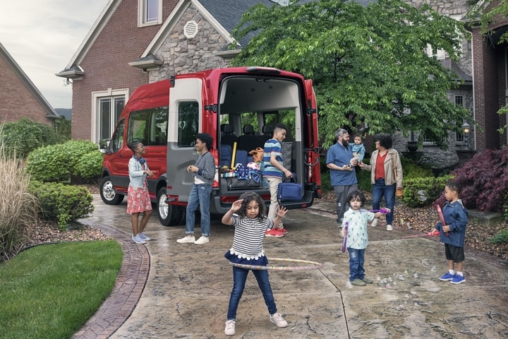 Un grupo de niños jugando enfrente de una van Ford Transit® 2023 con las puertas de carga abiertas
