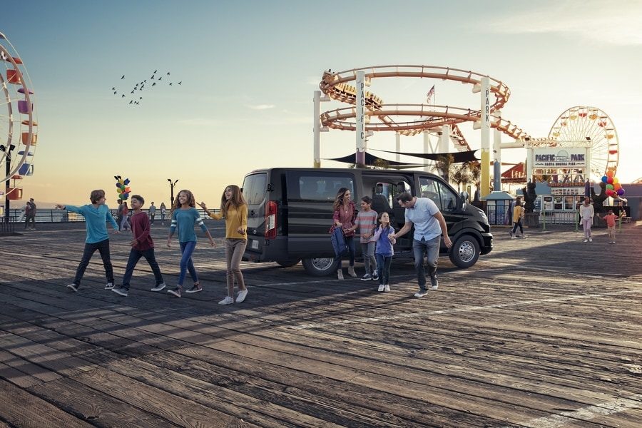 A walking away from a 2023 Ford Transit® van parked at an amusement park